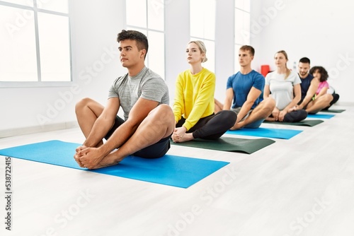 Group of young people concentrated stretching at sport center.