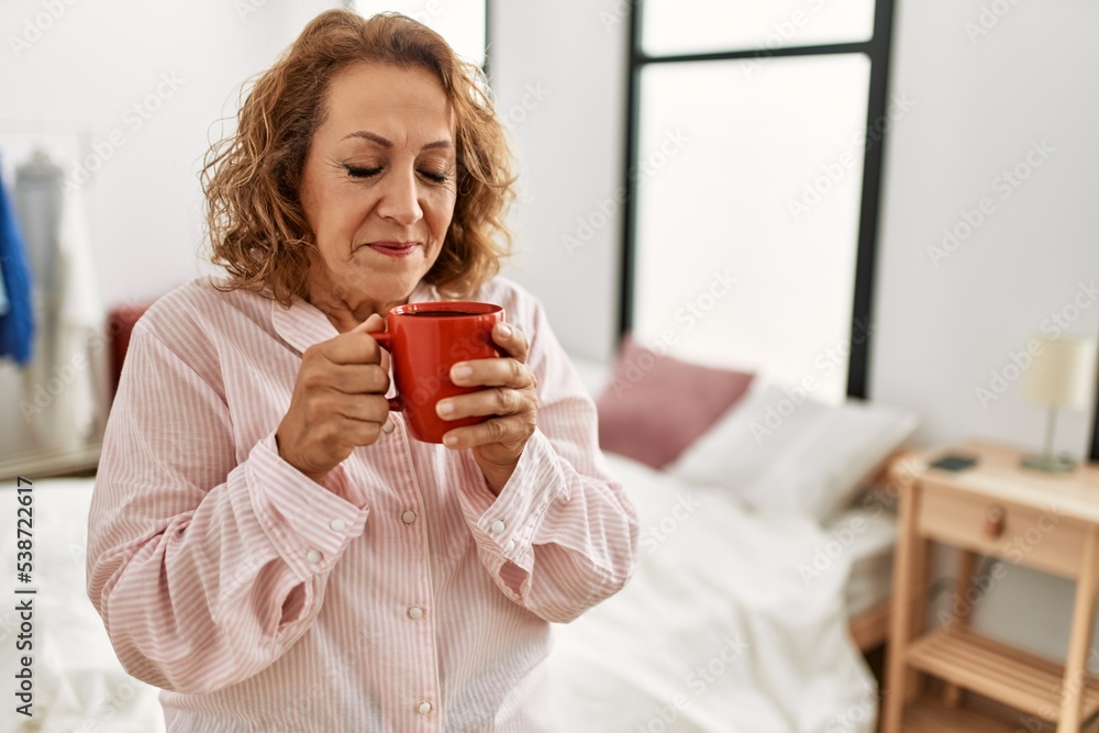 Middle age caucasian woman drinking coffee standing at bedroom. Middle age caucasian woman drinking coffee standing at bedroom.