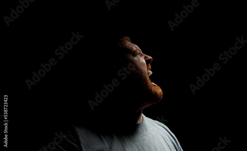 Screaming angry man on a dark background.