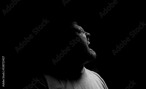 Screaming angry man on a dark background.