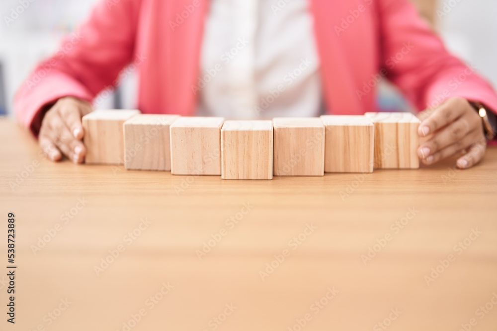 Young beautiful hispanic woman business worker sitting on table with wooden cubes at office Young beautiful hispanic woman business worker sitting on table with wooden cubes at office
