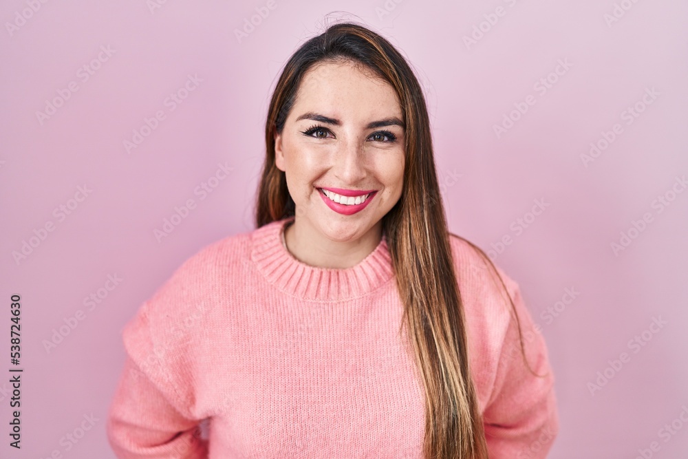 Fototapeta premium Young hispanic woman standing over pink background with a happy and cool smile on face. lucky person.