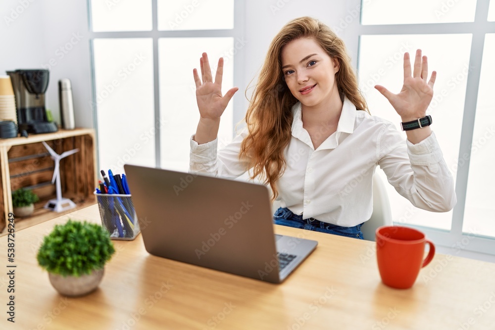 Young caucasian woman working at the office using computer laptop showing and pointing up with fingers number ten while smiling confident and happy. Young caucasian woman working at the office using computer laptop showing and pointing up with fingers number ten while smiling confident and happy.