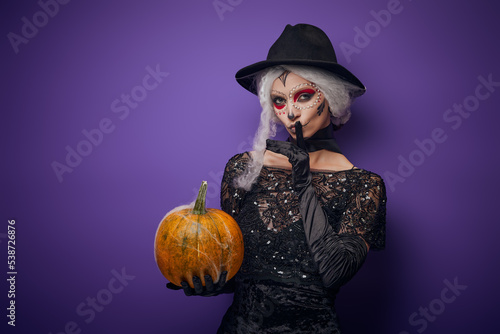 Witch with grey hair whispering in Halloween costume
