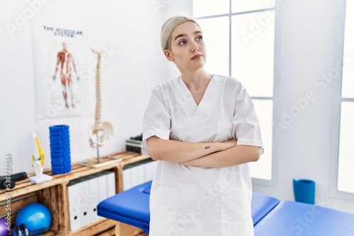 Young caucasian woman working at pain recovery clinic looking to the side with arms crossed convinced and confident © Krakenimages.com