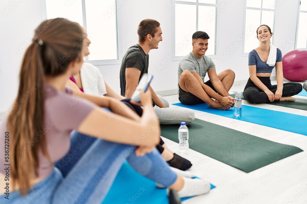 Group of young hispanic people smiling happy relaxing and using smartphone at sport center.