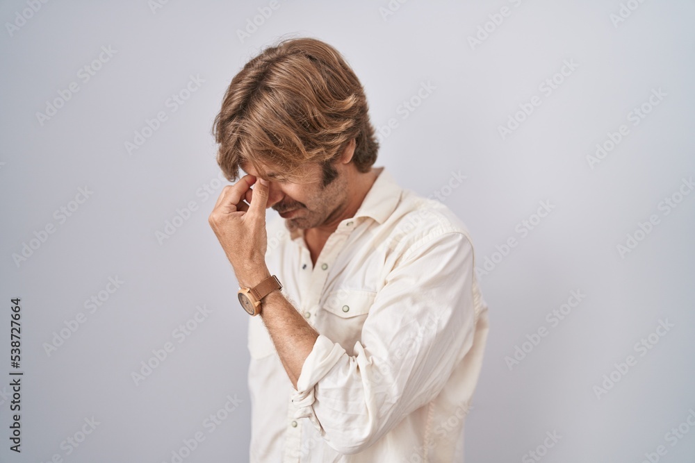 Middle age man standing over isolated background tired rubbing nose and eyes feeling fatigue and headache. stress and frustration concept. Middle age man standing over isolated background tired rubbing nose and eyes feeling fatigue and headache. stress and frustration concept.