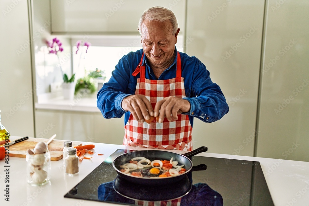 Senior man smiling confident pouring egg on frying pan at kitchen Senior man smiling confident pouring egg on frying pan at kitchen