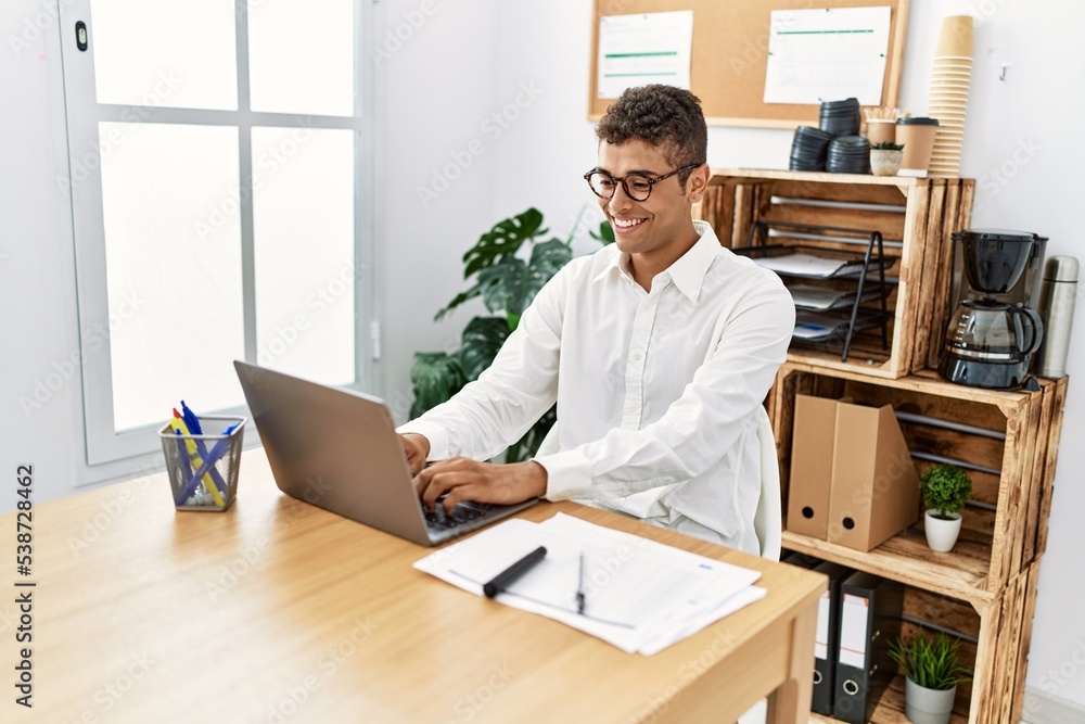 Young hispanic man working with laptop at business office Young hispanic man working with laptop at business office