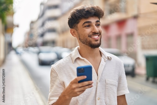 Young arab man smiling confident using smartphone at street © Krakenimages.com