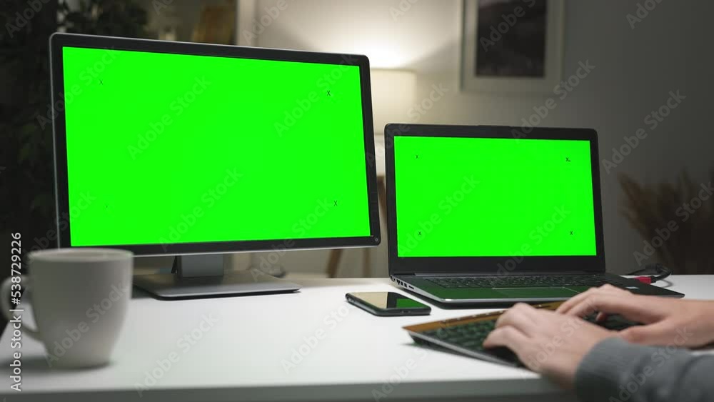 Young gamer sitting at home and playing using two chromakey screens. Freelancer working on project, programmer writing code Young gamer sitting at home and playing using two chromakey screens. Freelancer working on project, programmer writing code
