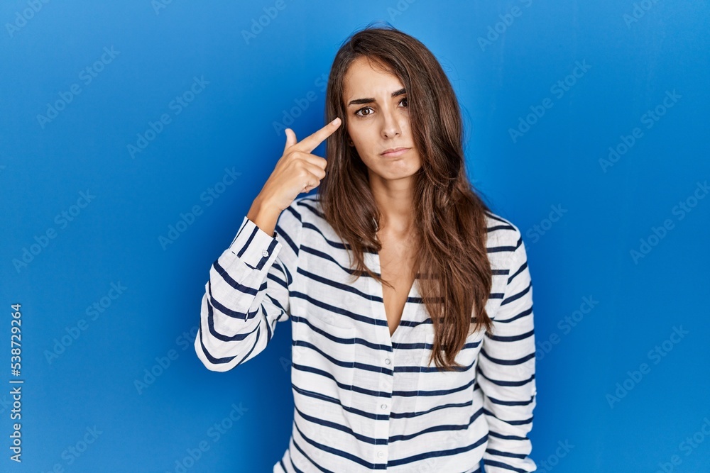 Young hispanic woman standing over blue isolated background shooting and killing oneself pointing hand and fingers to head like gun, suicide gesture. Young hispanic woman standing over blue isolated background shooting and killing oneself pointing hand and fingers to head like gun, suicide gesture.