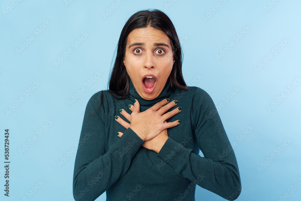 Young shocked woman against studio blue background Young shocked woman against studio blue background