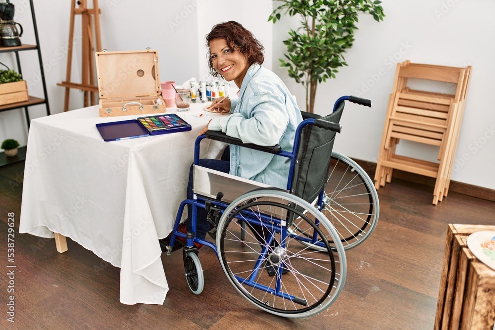Middle age hispanic disabled artist woman drawing sitting on wheelchair at art studio. Middle age hispanic disabled artist woman drawing sitting on wheelchair at art studio.