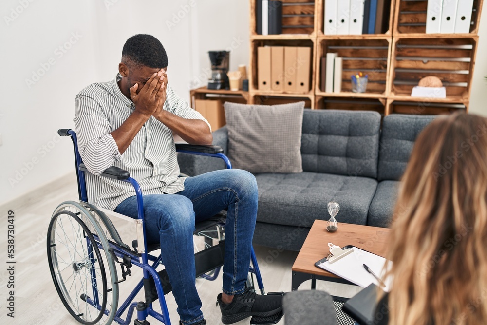 African american man doing therapy sitting on wheelchair with sad expression covering face with hands while crying. depression concept. African american man doing therapy sitting on wheelchair with sad expression covering face with hands while crying. depression concept.