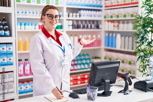 Young beautiful plus size woman pharmacist writing on notebook at pharmacy