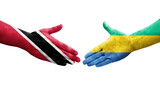 Handshake between Gabon and Trinidad Tobago flags painted on hands, isolated transparent image.