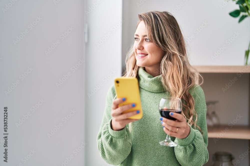 Young woman using smartphone drinking wine at home Young woman using smartphone drinking wine at home