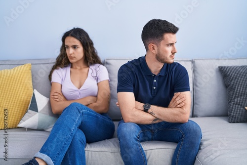 Young hispanic couple arguing sitting on sofa at home