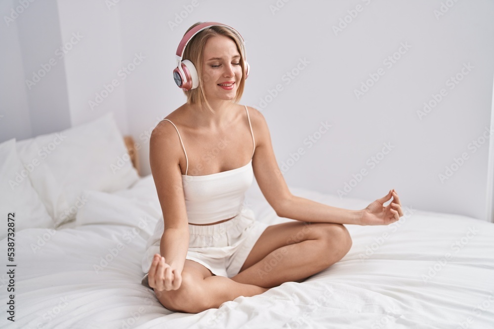 Young blonde woman doing yoga exercise sitting on bed at bedroom Young blonde woman doing yoga exercise sitting on bed at bedroom