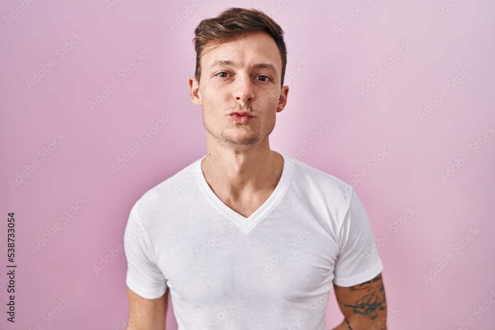 Caucasian man standing over pink background looking at the camera blowing a kiss on air being lovely and sexy. love expression. Caucasian man standing over pink background looking at the camera blowing a kiss on air being lovely and sexy. love expression.
