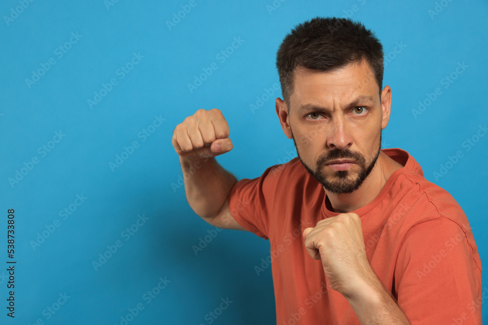 Naklejka premium Man ready to fight on light blue background, space for text