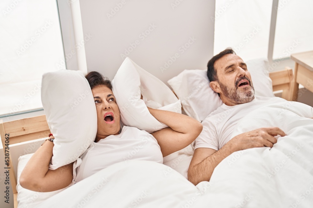 Middle age man and woman couple unhappy for snoring at bedroom Middle age man and woman couple unhappy for snoring at bedroom