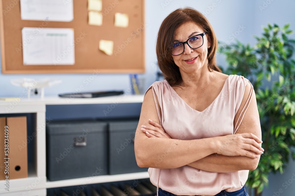Middle age woman business worker smiling confident standing with arms crossed gesture at office
