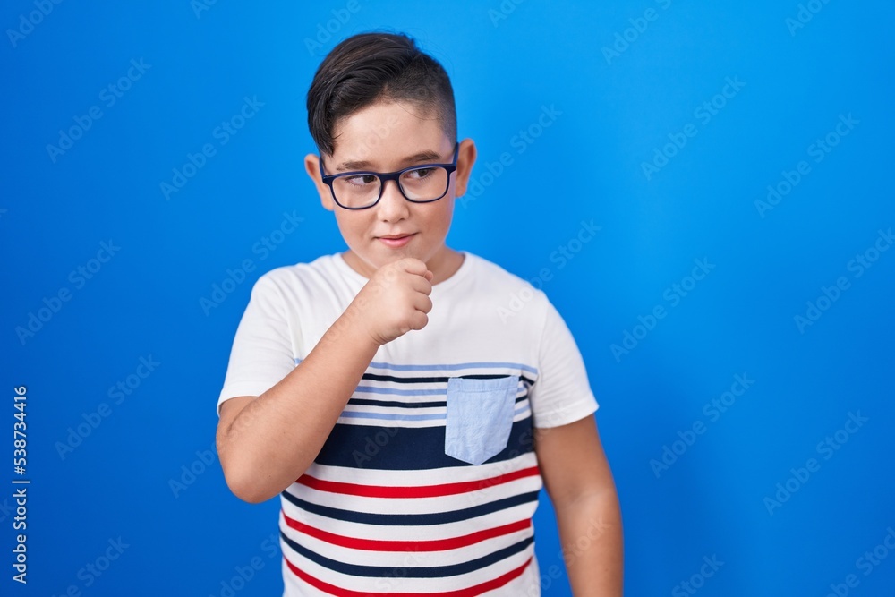 Young hispanic kid standing over blue background feeling unwell and coughing as symptom for cold or bronchitis. health care concept. Young hispanic kid standing over blue background feeling unwell and coughing as symptom for cold or bronchitis. health care concept.