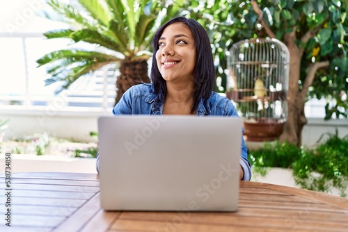 Hispanic brunette woman using laptop at the terrace