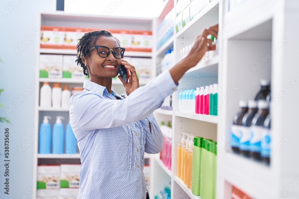 Middle age african american woman customer smiling confident talking on smartphone at pharmacy