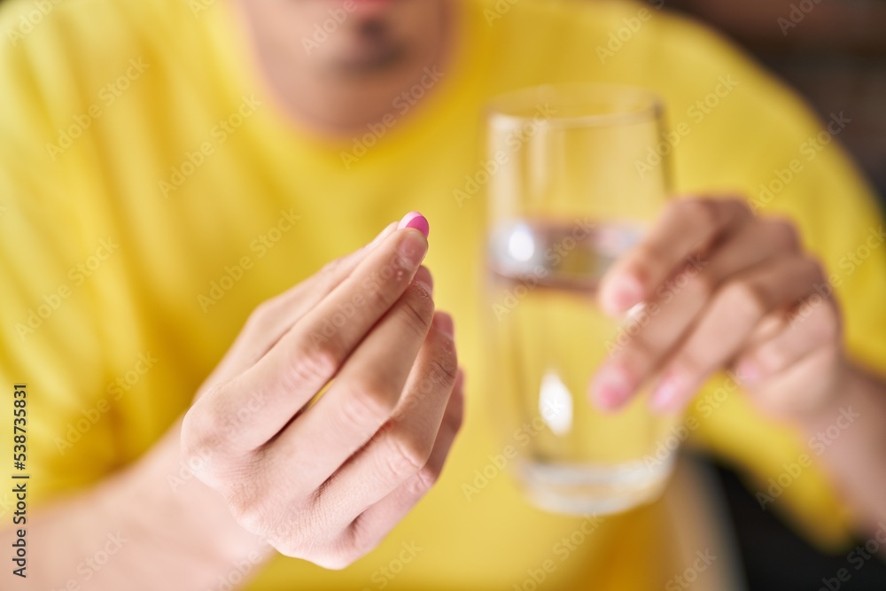 Young caucasian man holding pill and glass of water at home Young caucasian man holding pill and glass of water at home