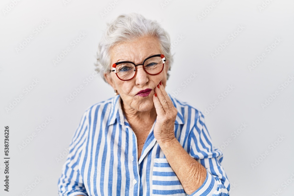 Senior woman with grey hair standing over white background touching mouth with hand with painful expression because of toothache or dental illness on teeth. dentist