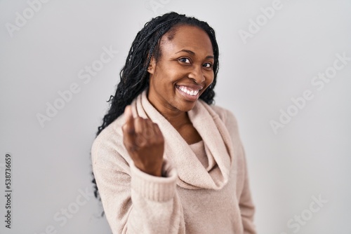 African woman standing over white background beckoning come here gesture with hand inviting welcoming happy and smiling