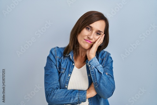 Middle age brunette woman wearing casual denim jacket over isolated background thinking looking tired and bored with depression problems with crossed arms. photo