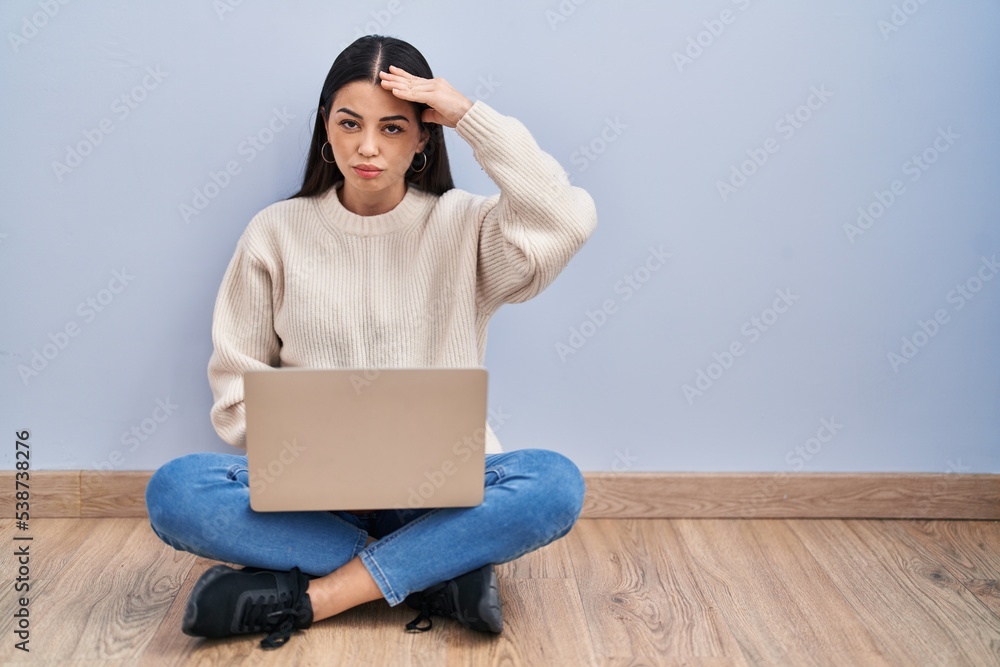 Young woman using laptop sitting on the floor at home worried and stressed about a problem with hand on forehead, nervous and anxious for crisis Young woman using laptop sitting on the floor at home worried and stressed about a problem with hand on forehead, nervous and anxious for crisis