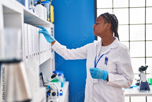 African american woman scientist holding binder at laboratory