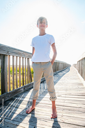 Fototapeta Naklejka Na Ścianę i Meble -  Child Youth Boy Standing in the Sun on a Boardwalk