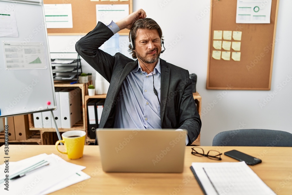 Handsome middle age man wearing call center agent headset at the office ...