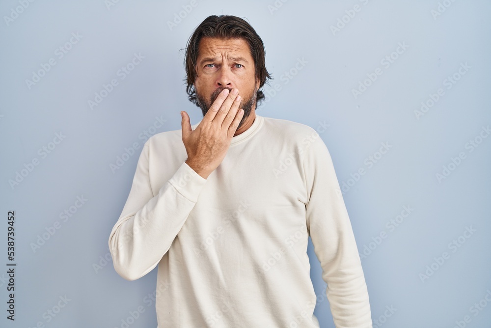 Handsome middle age man wearing casual sweater over blue background bored yawning tired covering mouth with hand. restless and sleepiness. Handsome middle age man wearing casual sweater over blue background bored yawning tired covering mouth with hand. restless and sleepiness.