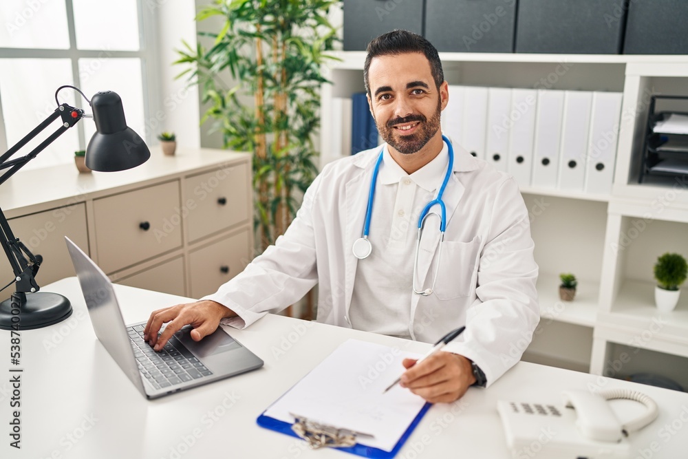 Young hispanic man wearing doctor uniform working at clinic Young hispanic man wearing doctor uniform working at clinic