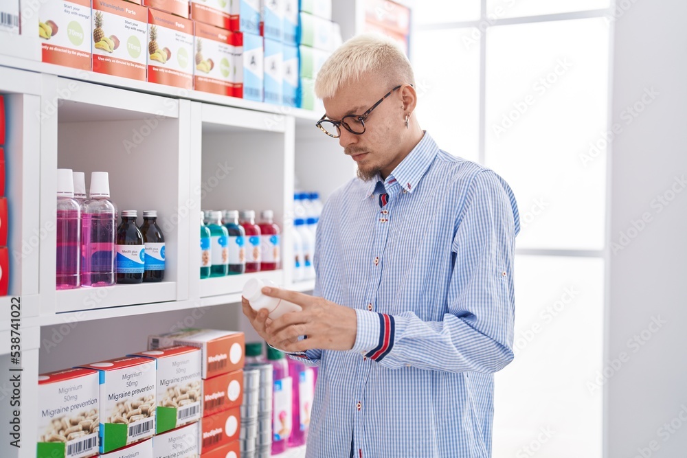 Young caucasian man customer looking pills bottle at pharmacy