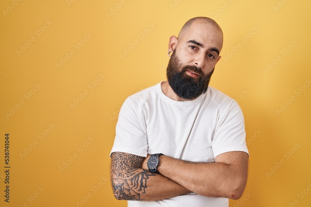 Young hispanic man with beard and tattoos standing over yellow background looking sleepy and tired, exhausted for fatigue and hangover, lazy eyes in the morning. Young hispanic man with beard and tattoos standing over yellow background looking sleepy and tired, exhausted for fatigue and hangover, lazy eyes in the morning.