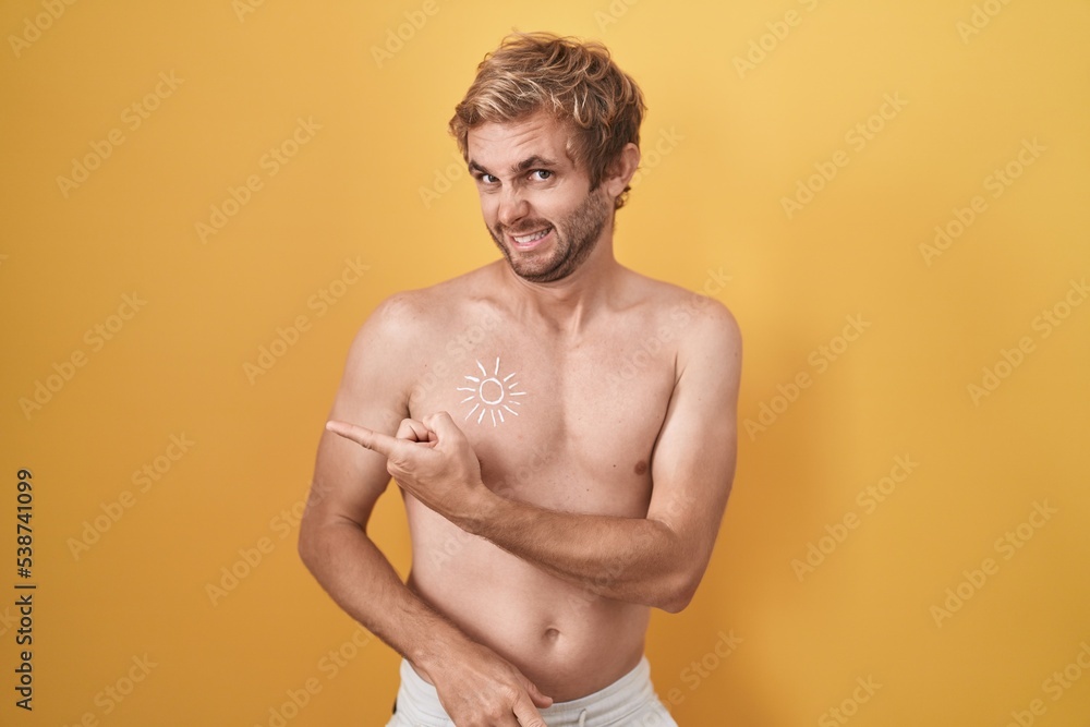 Caucasian man standing shirtless wearing sun screen pointing aside worried and nervous with forefinger, concerned and surprised expression