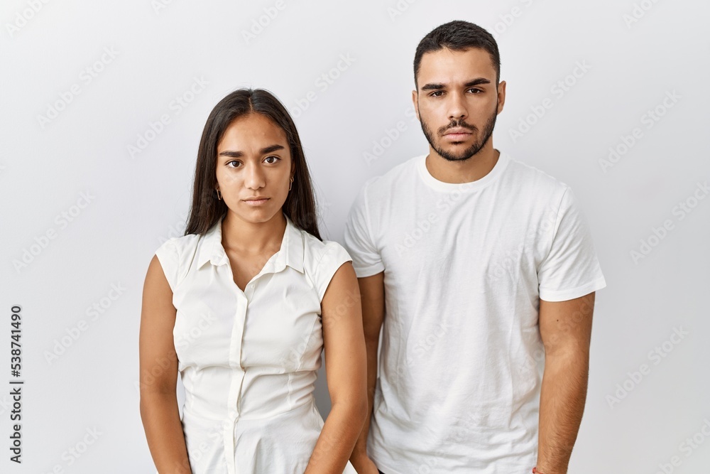 Young interracial couple standing together in love over isolated background relaxed with serious expression on face. simple and natural looking at the camera. Young interracial couple standing together in love over isolated background relaxed with serious expression on face. simple and natural looking at the camera.