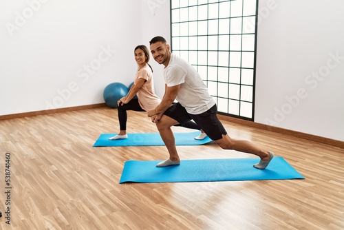 Latin man and woman couple smiling confident stretching at sport center