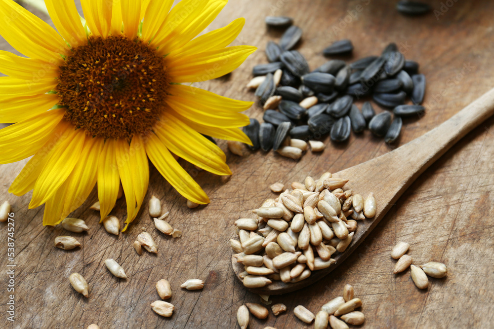 Sunflower seeds and flower on wooden table