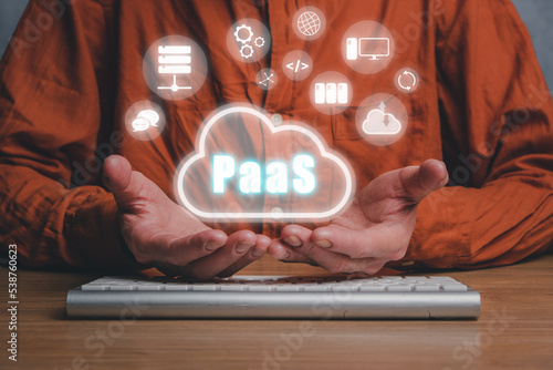 PaaS - Platform as a service, Man hand holding Paas icon on VR screen on desk background, Internet technology and development concept. photo