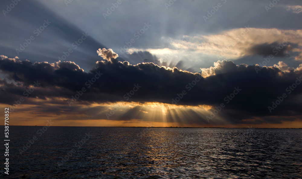 Rayos de sol cálidos vistos en el Mar Mediterráneo a través de un nube en el horizonte 