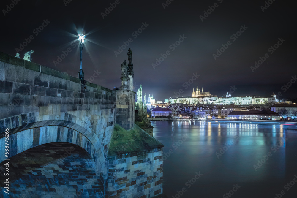 Charles bridge and Vltava river at night with blurred boat movement, Prague